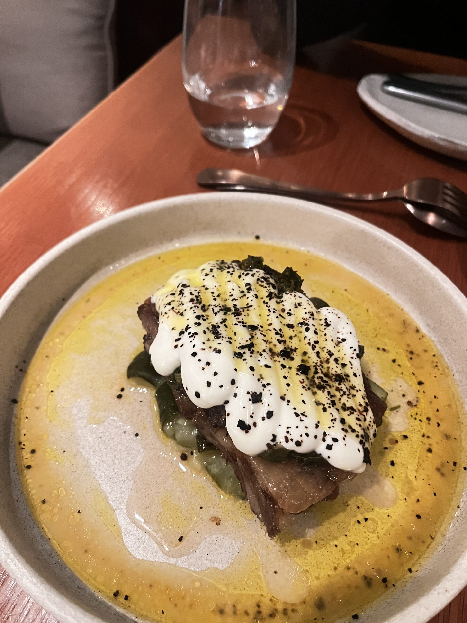 lamb neck served on a bed of soft zucchini and topped with yoghurt sauce